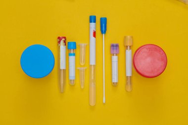 Tıbbi test tüpleri ve kavanozlar sarı arka planda test için.