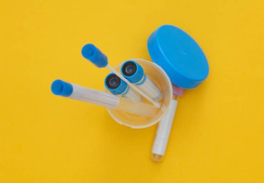 Tıbbi test tüpleri ve kavanozlar sarı arka planda test için.