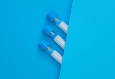 Mavi arka planda tıbbi boş kan tüpleri.