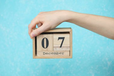 Kadının elinde ahşap blok takvimi var. Tarihi de Aralık 07, mavi beton arka plan.