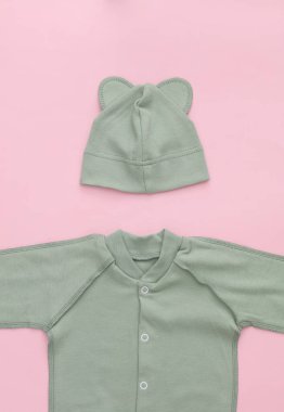 Yeni doğmuş bebek arabası ve pembe arka planda şapka. Üst Manzara. Düz yatıyordu