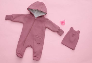 Pembe arka planda yeni doğmuş bebek kıyafetleri. Üst Manzara. Düz yatıyordu