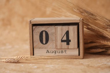 Tahta blok takvimi ve bej beton arka planda buğday başakları.