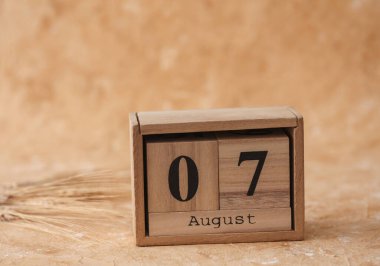 Tahta blok takviminde tarih 07 Ağustos ve bej beton arka planda buğday başakları