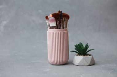 Gri beton arka planda depolama düzenleyicisindeki makyaj fırçaları