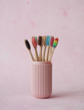 Plastik bir organizatör çantasında pembe beton arka planda bir dizi eko bambu diş fırçası.
