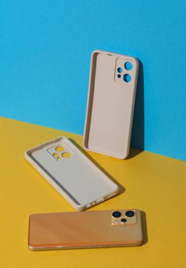 Beyaz koruyucu çantalar ve mavi sarı arka planda akıllı telefon.