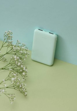 Yeşil arkaplanda beyaz elektrik bankası ve çiçekler