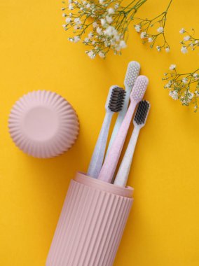 Sarı arkaplanda çiçekli plastik düzenleyici çantasındaki diş fırçaları