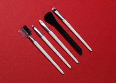 Kırmızı arkaplanda makyaj fırçaları