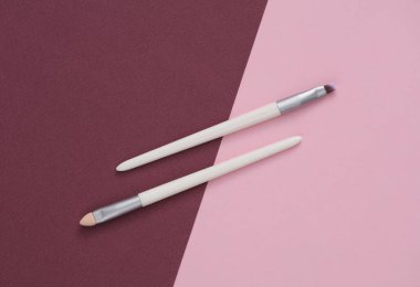 Bordo pembe arka planda makyaj fırçaları.