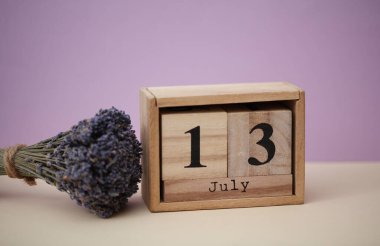 Tahta blok takvimi, 13 Temmuz tarihi ve bir buket kuru lavanta çiçeği.