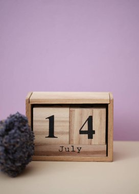 14 Temmuz tarihli ahşap blok takvimi ve bir buket kuru lavanta çiçeği.