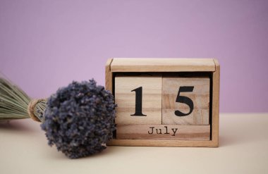 Tahta blok takvimi, tarihi 15 Temmuz ve bir buket kuru lavanta çiçeği.