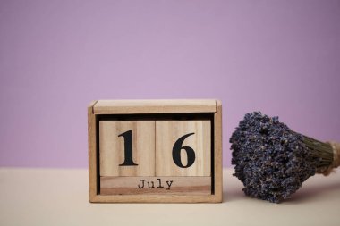Tahta blok takvimi. Tarihi 16 Temmuz ve bir buket kuru lavanta çiçeği.