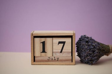 17 Temmuz tarihli ahşap blok takvimi ve bir buket kuru lavanta çiçeği.
