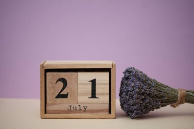 Tahta blok takvimi ve 21 Temmuz tarihi ve bir buket kuru lavanta çiçeği.