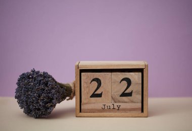 22 Temmuz tarihli ahşap blok takvimi ve bir buket kuru lavanta çiçeği.