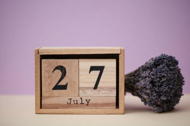 Tahta blok takvimi, tarihi 27 Temmuz ve bir buket kuru lavanta çiçeği.