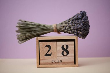 28 Temmuz tarihli ahşap blok takvimi ve bir buket kuru lavanta çiçeği.