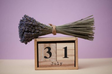 Tahta blok takvimi, 31 Temmuz tarihi ve bir buket kuru lavanta çiçeği.