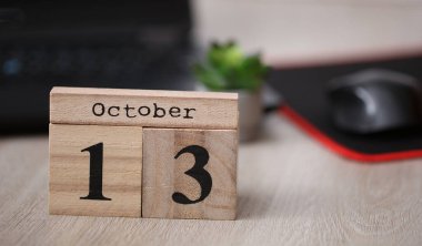 Masaüstünde 13 Ekim tarihli tahta takvim ve dizüstü bilgisayar