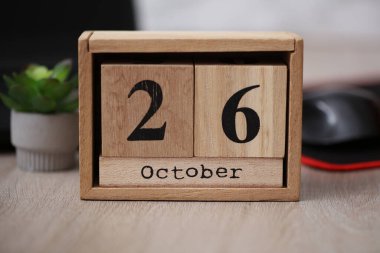 Masaüstünde 26 Ekim tarihli tahta takvim ve dizüstü bilgisayar