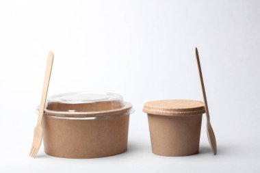 Tek kullanımlık karton yemek kutuları, tahta çatal ve beyaz arka planda kaşık. Eko kavramı