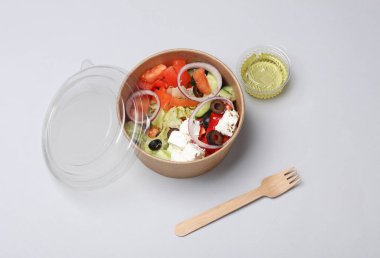 Gri arka planda tek kullanımlık karton bir kapta Yunan salatası