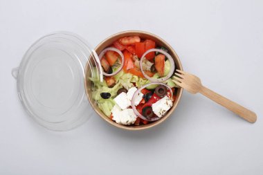 Gri arka planda tek kullanımlık karton bir kapta Yunan salatası