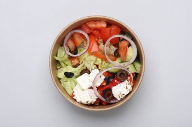 Gri arka planda tek kullanımlık karton bir kapta Yunan salatası