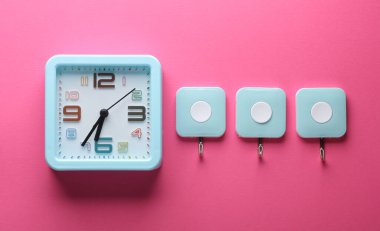 Pembe arka planda saat ve duvar kancaları