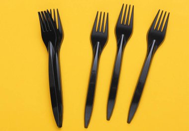 Sarı arka planda siyah plastik çatallar.