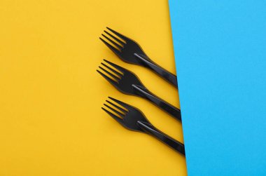 Mavi-sarı arkaplanda siyah plastik çatallar