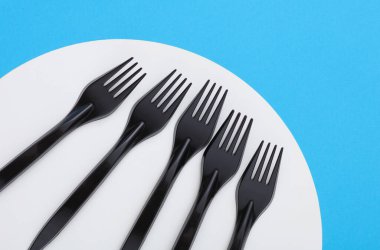 Mavi beyaz arkaplanda siyah plastik çatallar