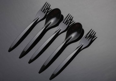 Siyah plastik kaşıklar ve çatallar koyu bir arkaplanda