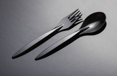 Siyah plastik kaşık ve çatal arka planda.