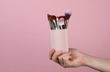 Pembe arka planda makyaj fırçaları olan plastik organizatör çantası.