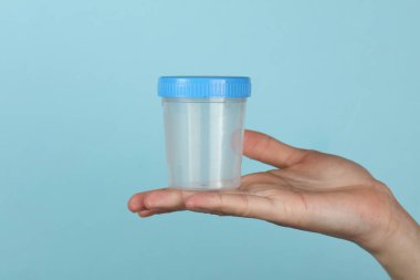 Mavi arka planda idrar testi kavanozu.