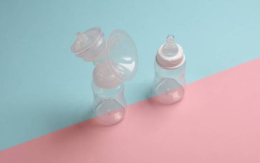 Göğüs pompası şişesi ve pembe mavi arka planda yeni doğmuş beslenme şişesi.