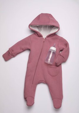 Kapüşonlu Romper ve beyaz arka planda yenidoğan için beslenme şişesi