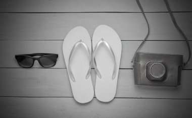 Plajda tatil kavramı, turizm. Yaz gezgini geçmişi. Parmak arası terlikler, retro kamera, tahta arka planda güneş gözlüğü. Üst Manzara. Düz yatıyordu