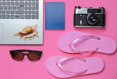 Yaz tatili. Yaz tatili gevşemesi. Laptop ve seyahat aksesuarları pembe arka planda. Stüdyo kısa. Plaj objesi. Üst Manzara. Düz yatıyordu