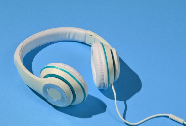 Mavi kağıt arka planda klasik beyaz kulaklıklar. Retro tarzı. 80 'ler. Popüler kültür. Asgari Müzik Konsepti