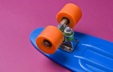 Mor arka planda modaya uygun hippi kaykayı. Minimalizm kavramı. Gençlik yaşam tarzı.