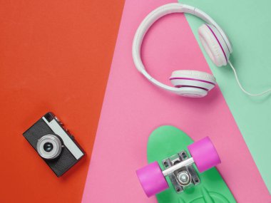 Hippi kıyafeti. Kulaklıklı kaykay, renkli arka planda retro kamera. Yaratıcı moda minimalizmi. Modaya uygun, modaya uygun. Asgari yaz eğlencesi. Müzik konsepti. Üst görünüm