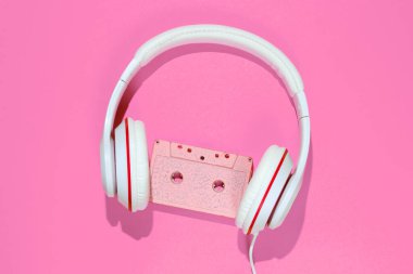 Pembe arka planda ses kaseti ve kulaklık. Retro müzik konsepti. Klasik arka plan. Disko partisi. Üst görünüm