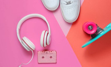 Hippi kıyafeti. Kulaklıklı kaykay, ses kaseti ve renkli arka planda spor ayakkabıları. Yaratıcı moda minimalizmi. Asgari yaz eğlencesi. Pop sanat. 80 'ler. Müzik konsepti. Üst görünüm