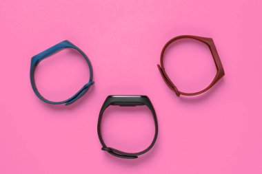 Pembe arka planda değiştirilebilir bilezikleri olan akıllı saat. Fitness takip cihazı. Modern aygıtlar