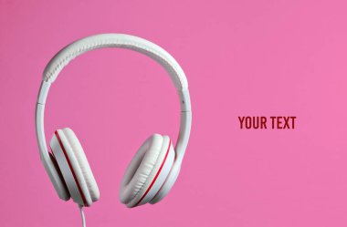 Beyaz klasik kulaklıklar pembe arka planda izole edilmiş. Retro tarzı. Minimalist müzik konsepti. Boşluğu kopyala